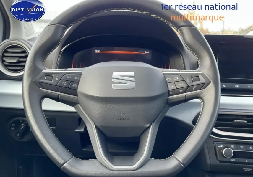 Vue rapprochée du volant cuir noir multifonction de la SEAT Ibiza 2025 avec tableau de bord digital en arrière-plan.