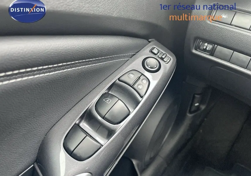 Vue rapprochée des commandes de lève-vitres côté conducteur sur la porte intérieure noire du Nissan Juke blanc nacré 2024.