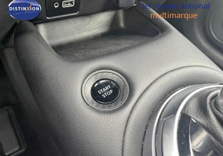 Gros plan sur le bouton start/stop et la console centrale en cuir noir du Nissan Juke blanc nacré 2024.