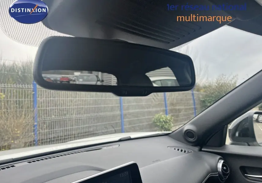 Intérieur du Nissan Juke blanc nacré, vue du tableau de bord côté passager avec rétroviseur et écran tactile allumé.