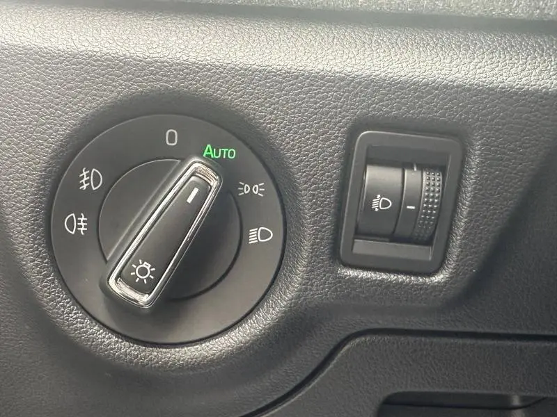 Gros plan sur le sélecteur de phares noir et molette de réglage d'intensité lumineuse dans l'habitacle d'une Skoda Scala noire.