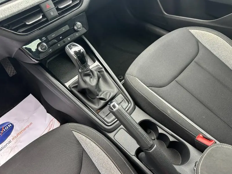 Vue intérieure centrée sur la console centrale noire avec levier de vitesse automatique et sièges tissu noir/gris de la Skoda Scala.