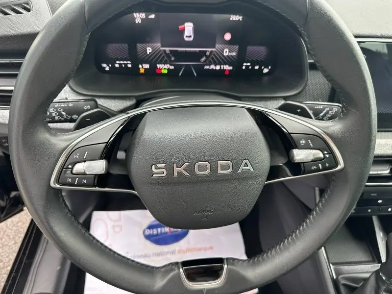 Vue rapprochée du volant cuir noir multifonction SKODA avec tableau de bord numérique affichant les informations de conduite.