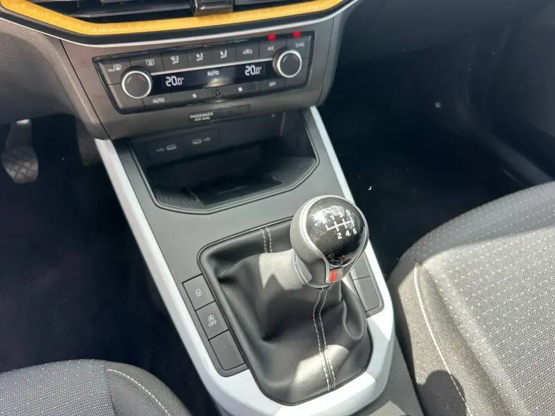 Gros plan sur la console centrale d'une SEAT Arona 2025 avec levier de vitesse manuel et commandes de climatisation.
