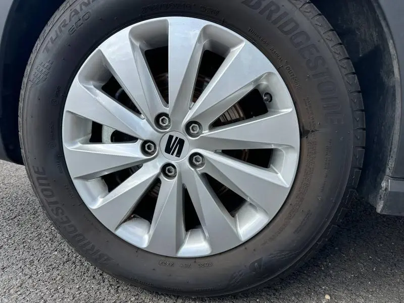 Gros plan sur la jante alu argentée avec logo SEAT au centre, montée sur pneu Bridgestone d'un SEAT Arona blanc.