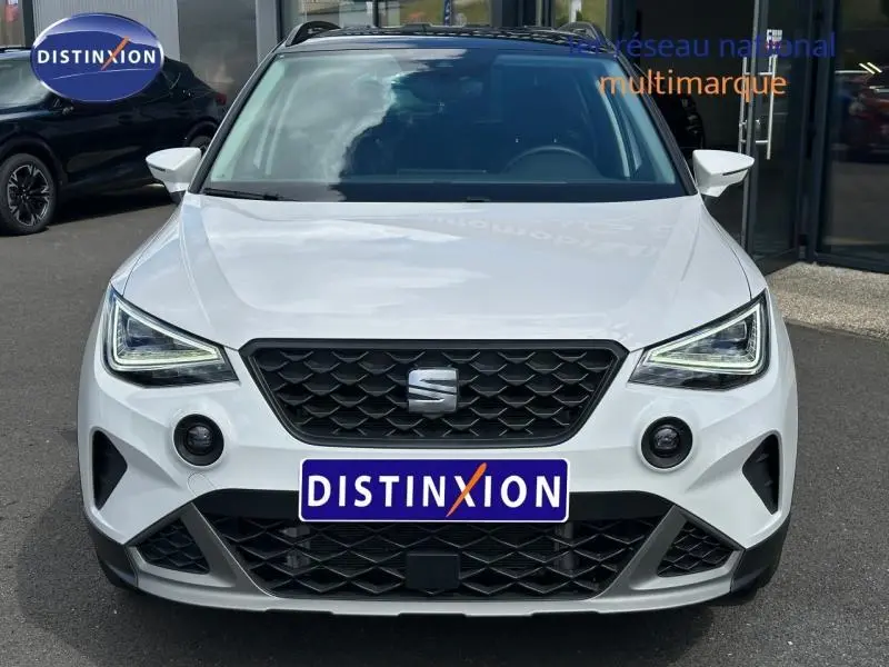 Vue avant d'un SEAT Arona blanc Candy avec toit noir Minuit, calandre noire et phares LED anguleux.