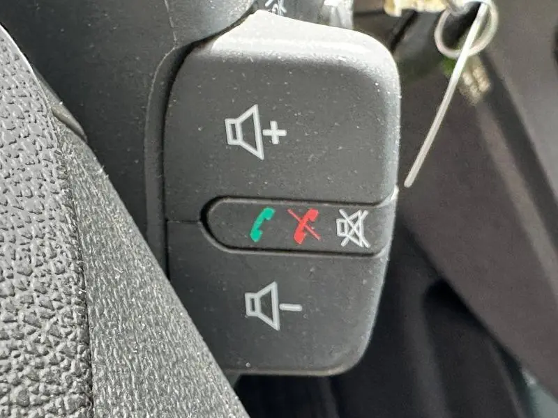 Boutons de commande audio et téléphone au volant d'un Renault Kangoo Express blanc minéral électrique, vue rapprochée côté conducteur.