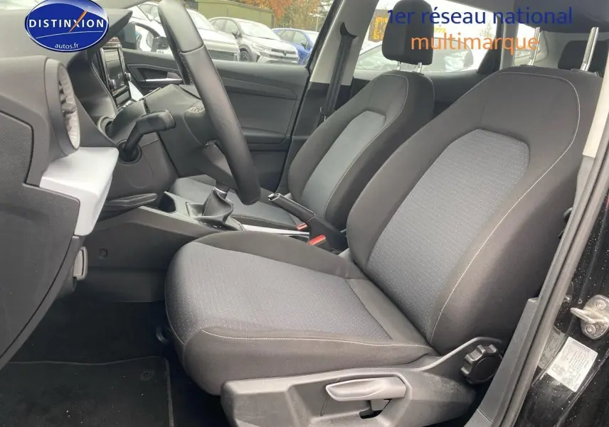 Vue intérieure côté conducteur de la SEAT Ibiza noir minuit 2025, montrant les sièges tissu gris et la boîte manuelle.