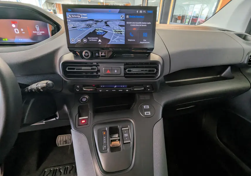 Vue intérieure du tableau de bord du Peugeot Rifter 2025 avec écran tactile central et commandes de boîte automatique.