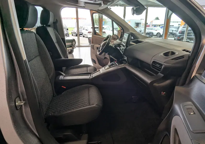 Vue intérieure côté gauche du Peugeot Rifter gris Artense 2025, montrant les sièges tissu et le tableau de bord moderne.