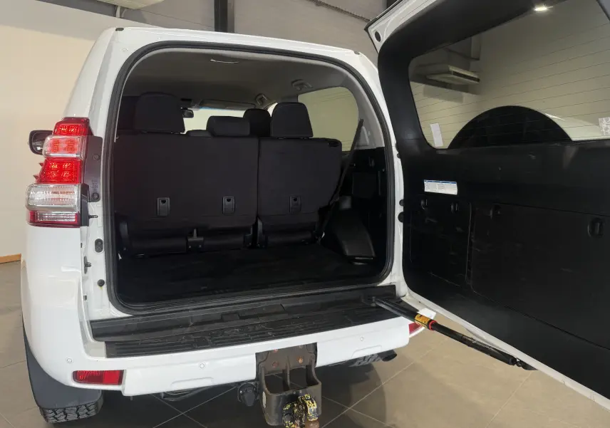 Vue arrière ouverte du Toyota Land Cruiser blanc 2015, montrant l'intérieur du coffre et l'attelage de remorque.