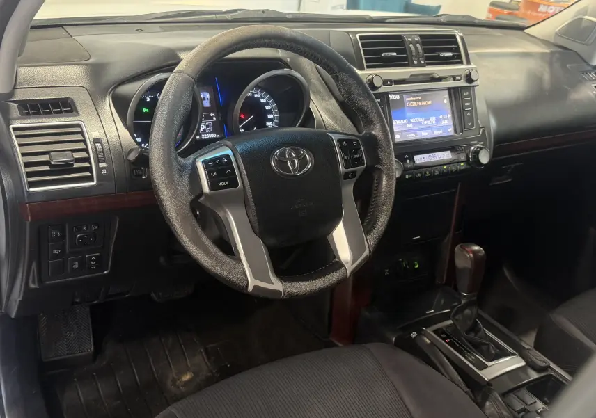 Vue intérieure du tableau de bord et volant du Toyota Land Cruiser 2015, avec boîte automatique et écran central tactile.