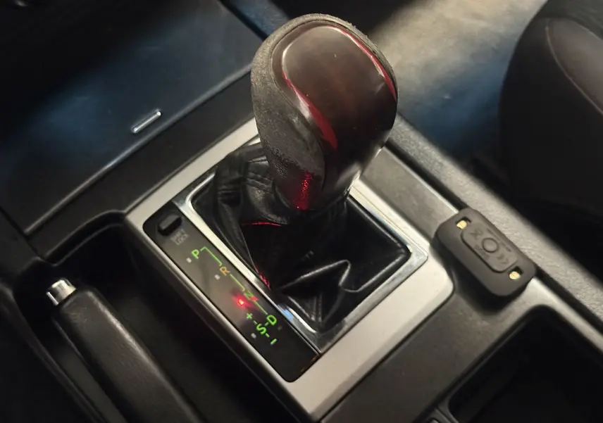 Gros plan sur le levier de vitesses automatique noir du Toyota Land Cruiser blanc, version 2.8 D-4D 2015, avec indicateurs lumineux.