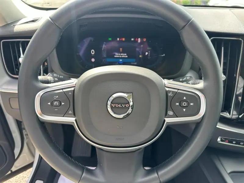 Vue frontale du volant cuir noir du Volvo XC60 2024 avec commandes multifonctions et tableau de bord numérique.