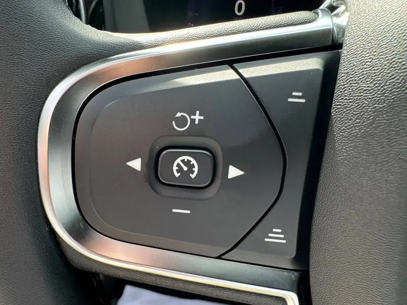 Gros plan sur les commandes de régulateur de vitesse au volant d’un Volvo XC60 blanc cristal métallisé 2024.