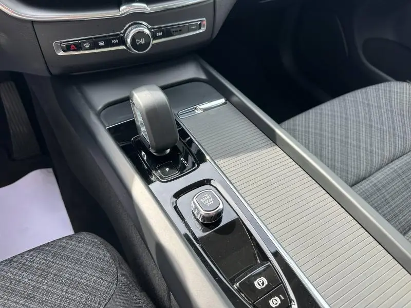 Vue rapprochée de la console centrale noire du Volvo XC60 2024 avec levier de vitesse et bouton start/stop.