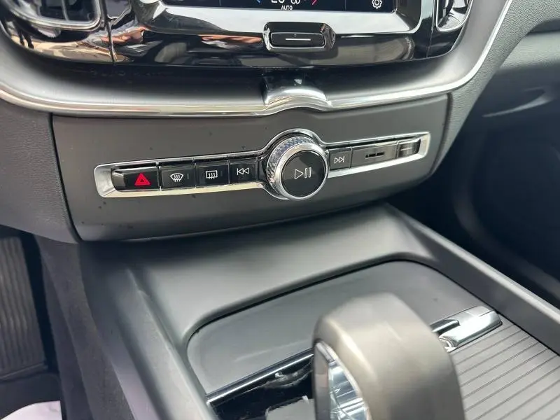 Vue rapprochée de la console centrale intérieure du Volvo XC60 blanc, avec commandes audio et climatisation chromées.