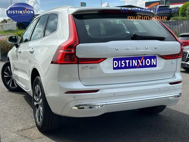 Vue 3/4 arrière droite d'un Volvo XC60 blanc cristal métallisé avec feux arrière LED et détails chromés.