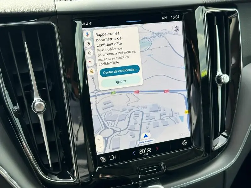 Vue rapprochée de l’écran tactile central noir du Volvo XC60 blanc, affichant une carte GPS avec menu confidentialité.