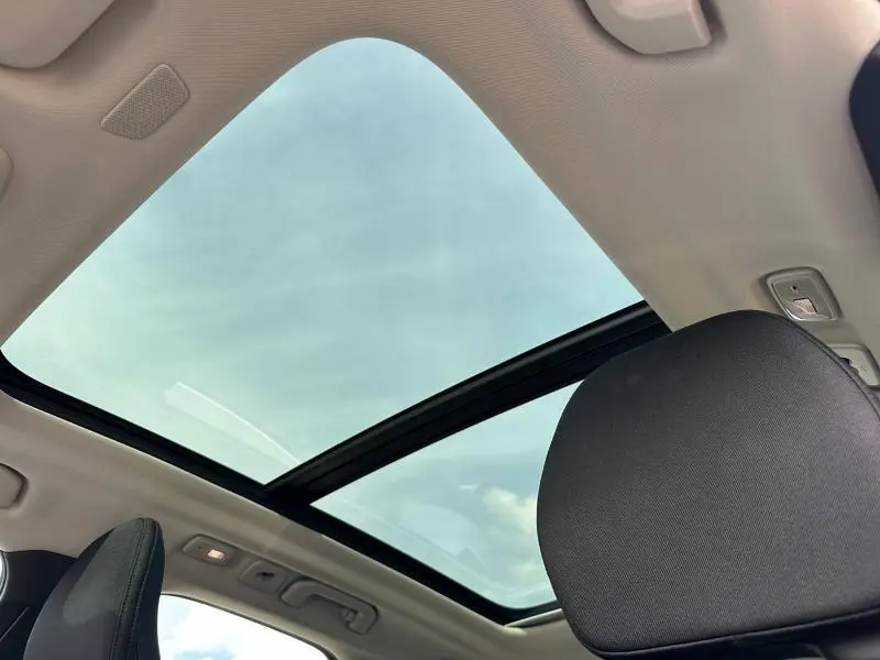 Vue intérieure du toit panoramique en verre du Volvo XC60 blanc, avec appui-tête avant noir visible au premier plan.