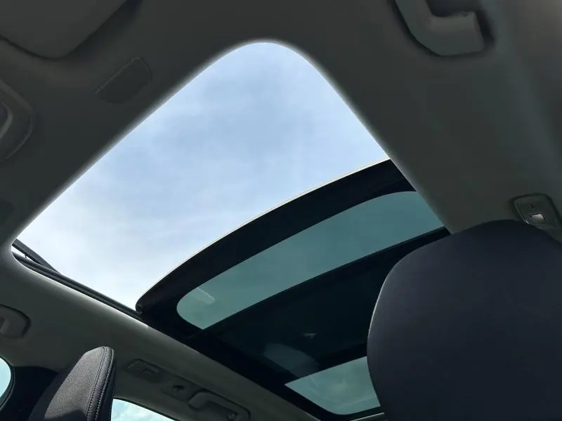 Vue intérieure du toit panoramique en verre du Volvo XC60 blanc cristal métallisé 2024, avec ciel visible à travers.