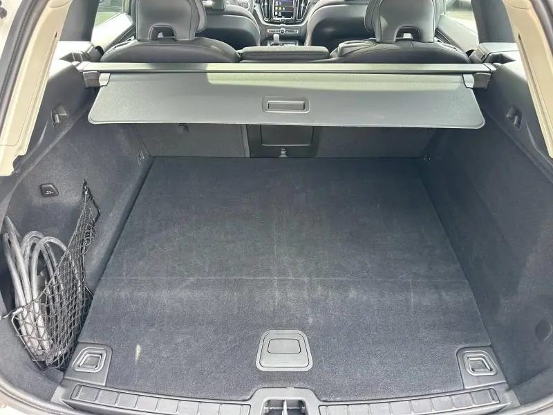 Vue intérieure du coffre spacieux du Volvo XC60 blanc, avec cache-bagages et banquette arrière rabattable visible.