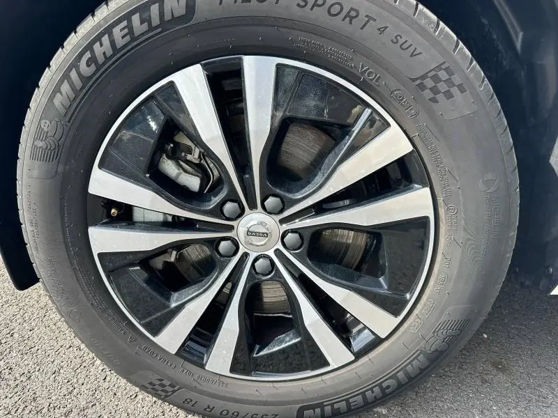 Gros plan sur la jante alliage bicolore et pneu Michelin d'un Volvo XC60 blanc cristal métallisé.