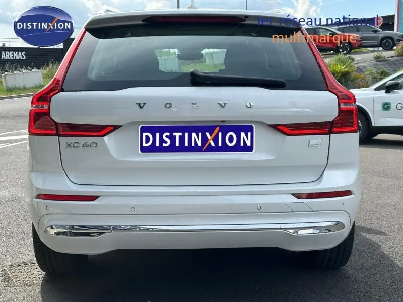 Vue arrière d'un Volvo XC60 T6 AWD blanc cristal métallisé avec feux LED et détails chromés sur le pare-chocs.