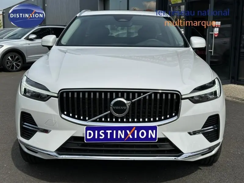 Vue frontale d'un Volvo XC60 blanc cristal métallisé avec calandre chromée et phares LED distinctifs.