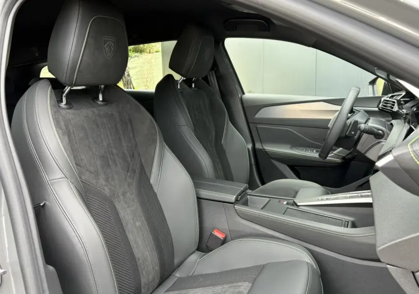 Vue intérieure côté conducteur du Peugeot 308 SW gris Sélénium, mettant en valeur les sièges Alcantara noirs et le volant compact GT.