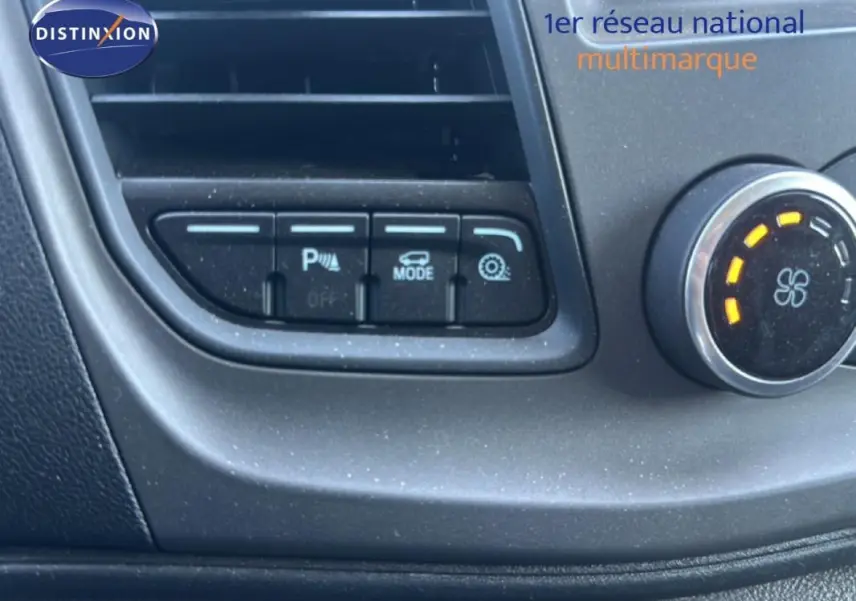 Détail du tableau de bord du Ford Transit Custom blanc 2021, montrant les boutons de réglage et la molette de ventilation.