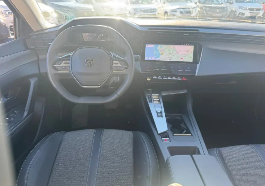 Vue intérieure avant du Peugeot 408 Hybrid 145 e-DCS6 Allure 2025, volant compact et écran tactile central visible.