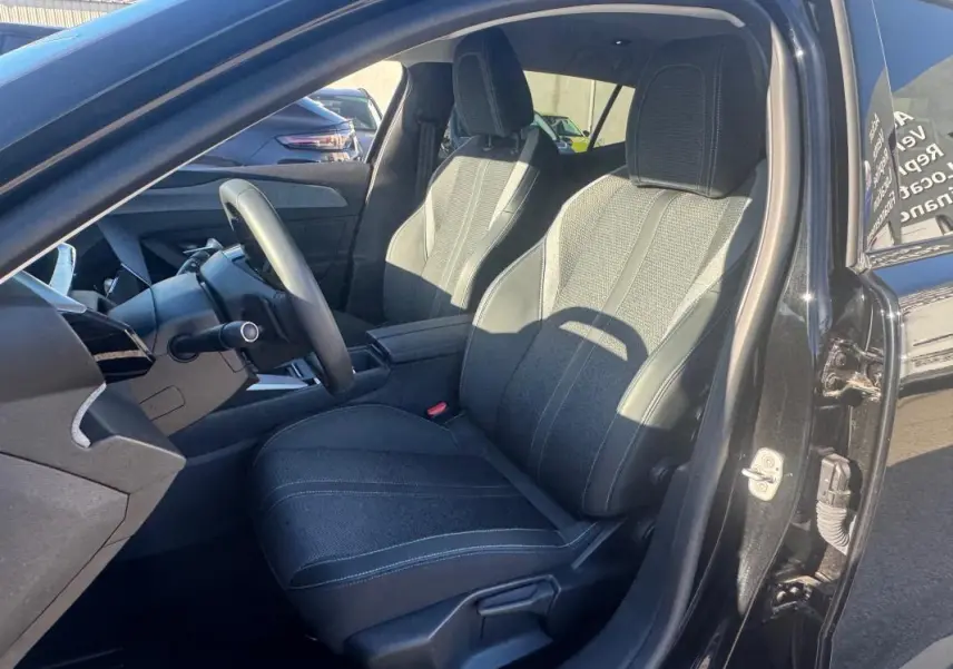 Vue intérieure côté conducteur du Peugeot 408 Hybrid 145 Allure 2025 noir, mettant en valeur les sièges et le volant.