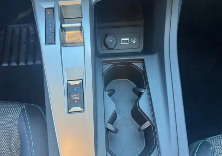 Vue plongeante sur la console centrale noire du Peugeot 408 Hybrid 145 e-DCS6 Allure 2025 avec sélecteur de boîte auto et porte-gobelets.
