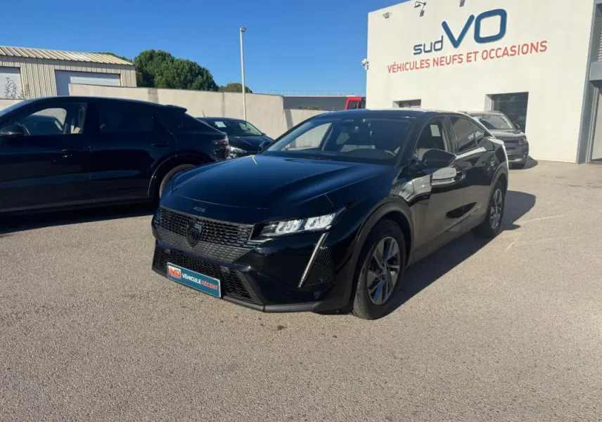 PEUGEOT 408 Hybrid 145 e-DCS6 Allure noir en 3/4 avant droit sur parking devant un bâtiment sud VO.