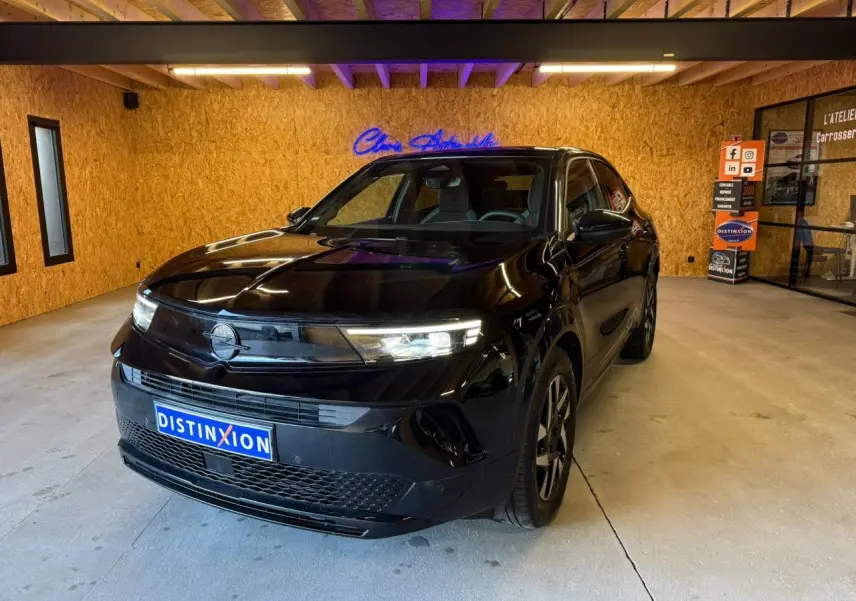 Opel Mokka noir vue 3/4 avant droit en intérieur, avec calandre Vizor et phares LED allumés.