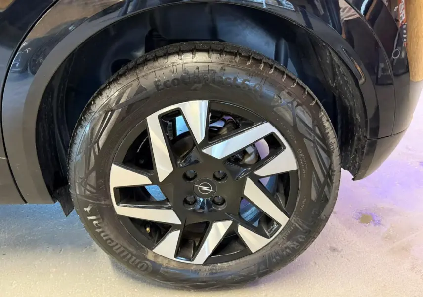 Gros plan sur la roue avant droite noire et argentée du SUV Opel Mokka noir avec jante alliage 17 pouces diamantée.