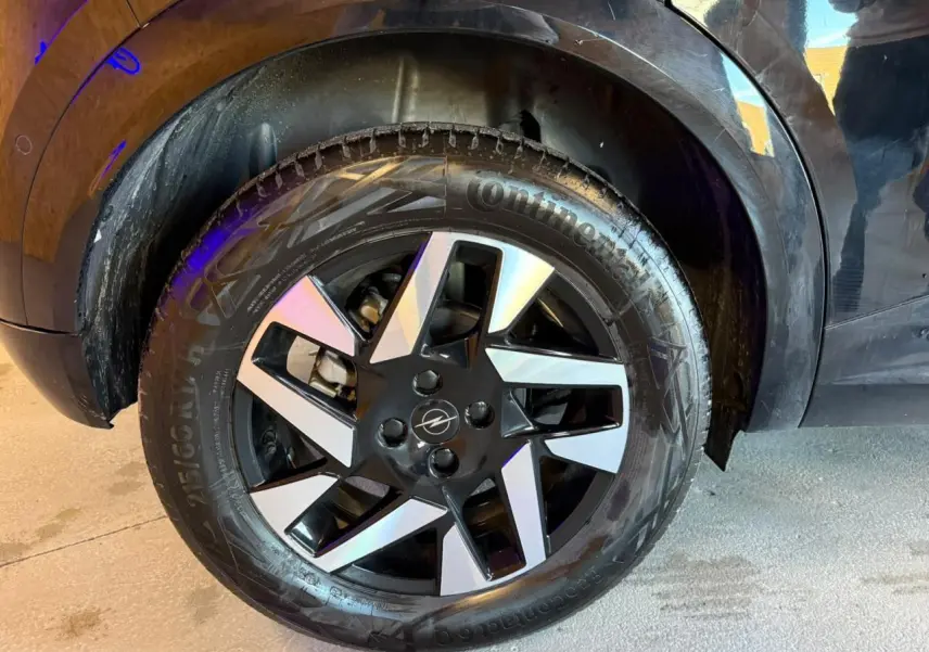 Gros plan sur la roue avant droite noire et argentée d’un Opel Mokka noir avec jante alliage 17 pouces diamantée.