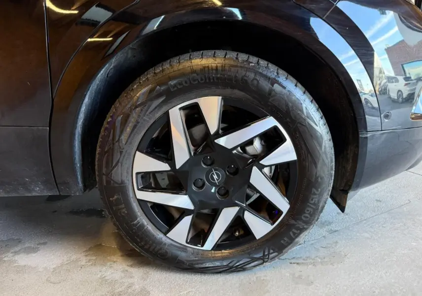 Gros plan sur la roue avant droite noire d’un Opel Mokka 2025 avec jante alliage diamantée bicolore.