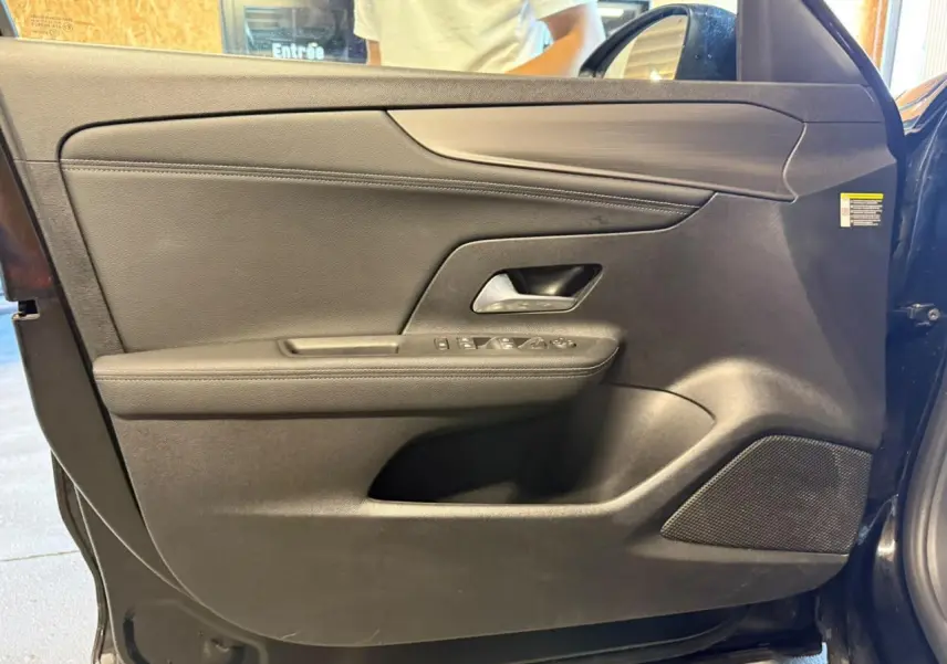 Vue intérieure de la porte avant gauche noire de l’Opel Mokka 2025 avec commandes électriques et haut-parleur intégré.