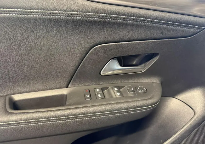 Gros plan sur la porte intérieure côté conducteur noire avec commandes des vitres et poignée chromée du Opel Mokka 2025.