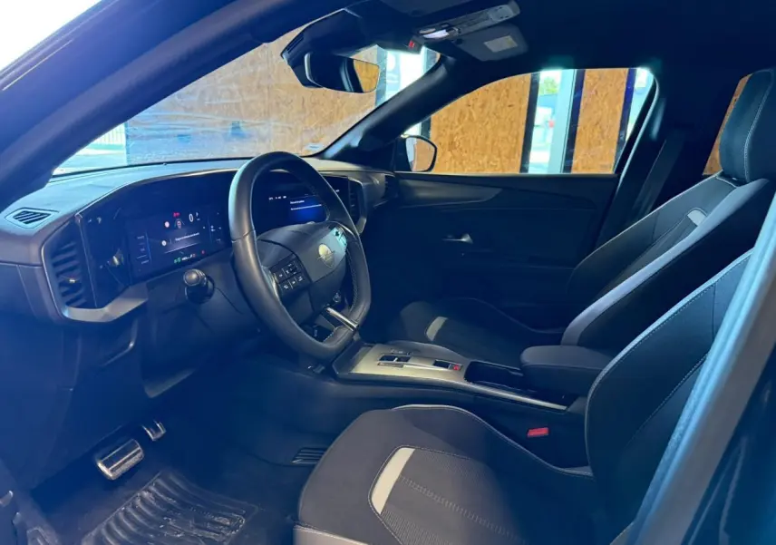 Vue intérieure côté conducteur de l'Opel Mokka 2025, sièges noirs avec inserts gris et tableau de bord numérique.