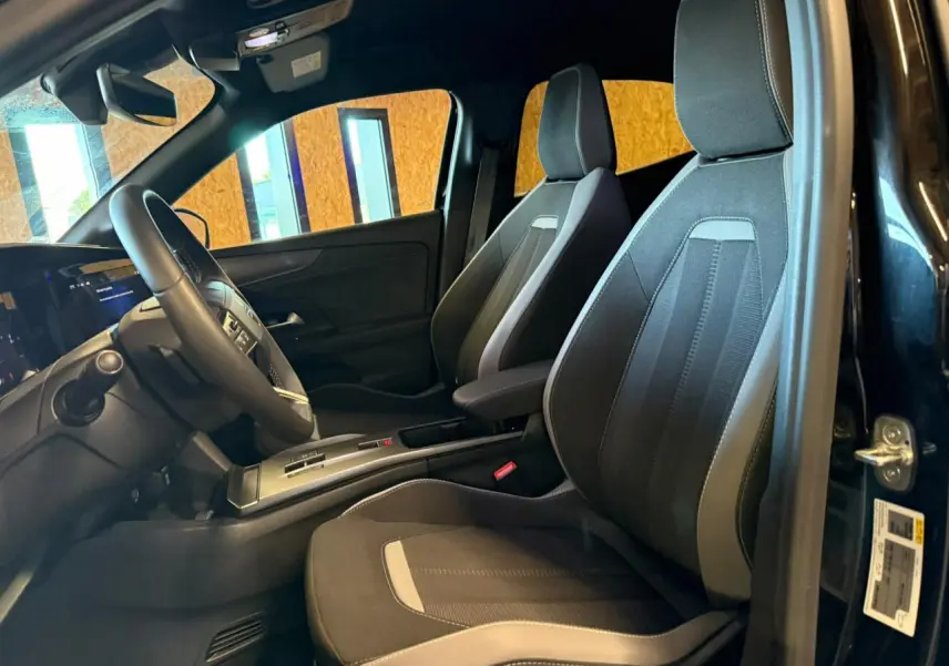 Vue intérieure côté conducteur de l'Opel Mokka noire, sièges tissu noir/gris et volant TEP avec console centrale.