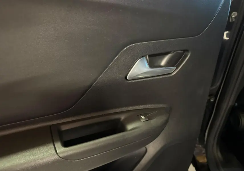 Gros plan sur la porte arrière droite noire de l'Opel Mokka 2025, avec poignée intérieure argentée et bouton de vitre électrique.