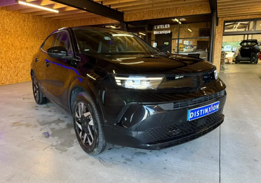 Opel Mokka noir vue 3/4 avant droit, calandre Vizor noire et jantes alliage 17'' diamantées, en intérieur d'atelier.