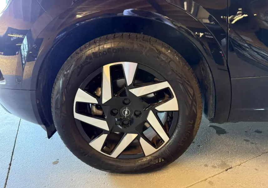 Gros plan sur la roue avant gauche noire d’un Opel Mokka 2025 avec jante alliage diamantée bicolore.