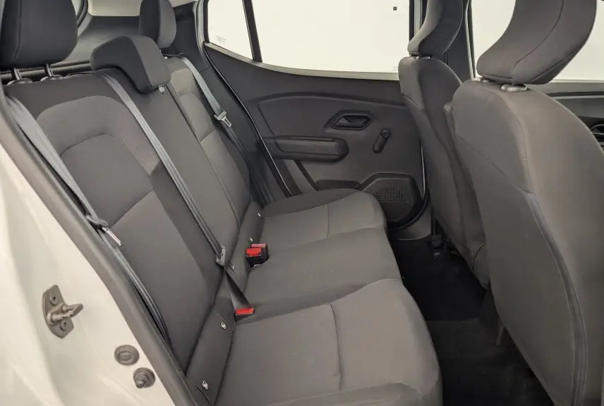 Vue intérieure arrière de la Dacia Sandero blanche 2022, montrant la banquette arrière en tissu gris avec ceintures de sécurité.
