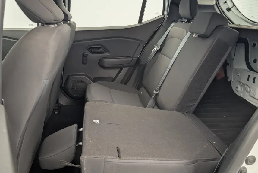 Vue intérieure côté droit de la banquette arrière rabattue en partie d'une Dacia Sandero blanche, soulignant l'espace de chargement.