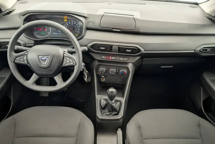 Vue intérieure avant de la Dacia Sandero blanche 2022, tableau de bord et volant avec commandes multifonctions.