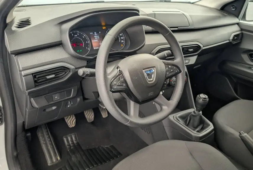 Vue intérieure côté conducteur de la Dacia Sandero blanche 2022, volant mousse et tableau de bord avec écran TFT.